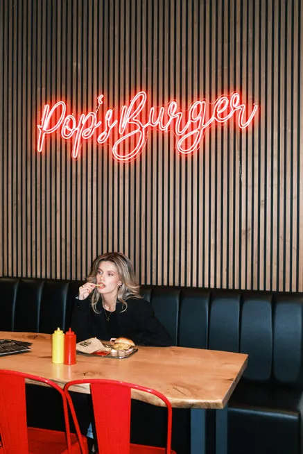 Roter Neonschriftzug POPs Burger an dunkler Wand im Gastraum