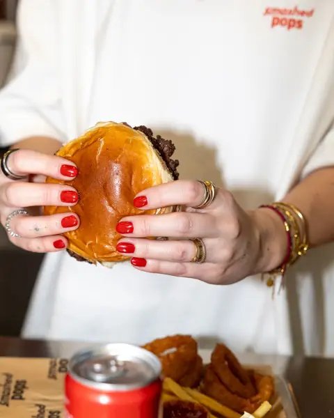 Smashed-Pops-Burger in zwei Händen gehalten